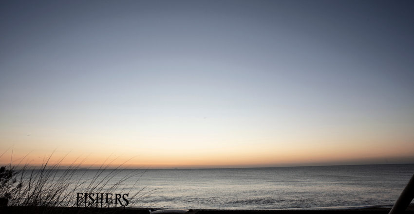 Fishers Distillery sign against the beach at sunrise