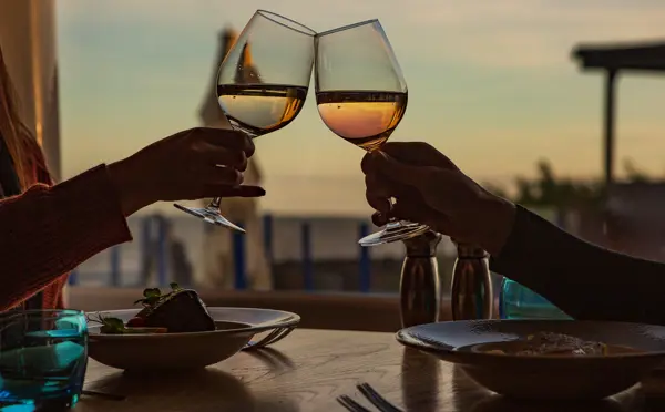 Toasting two glasses with sunset in background